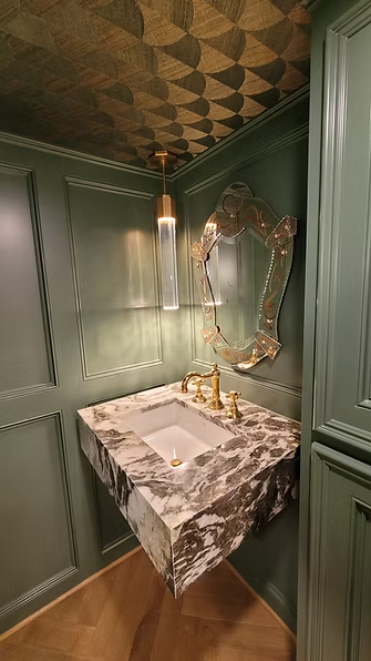 Powder room with green paneling and a stone vanity